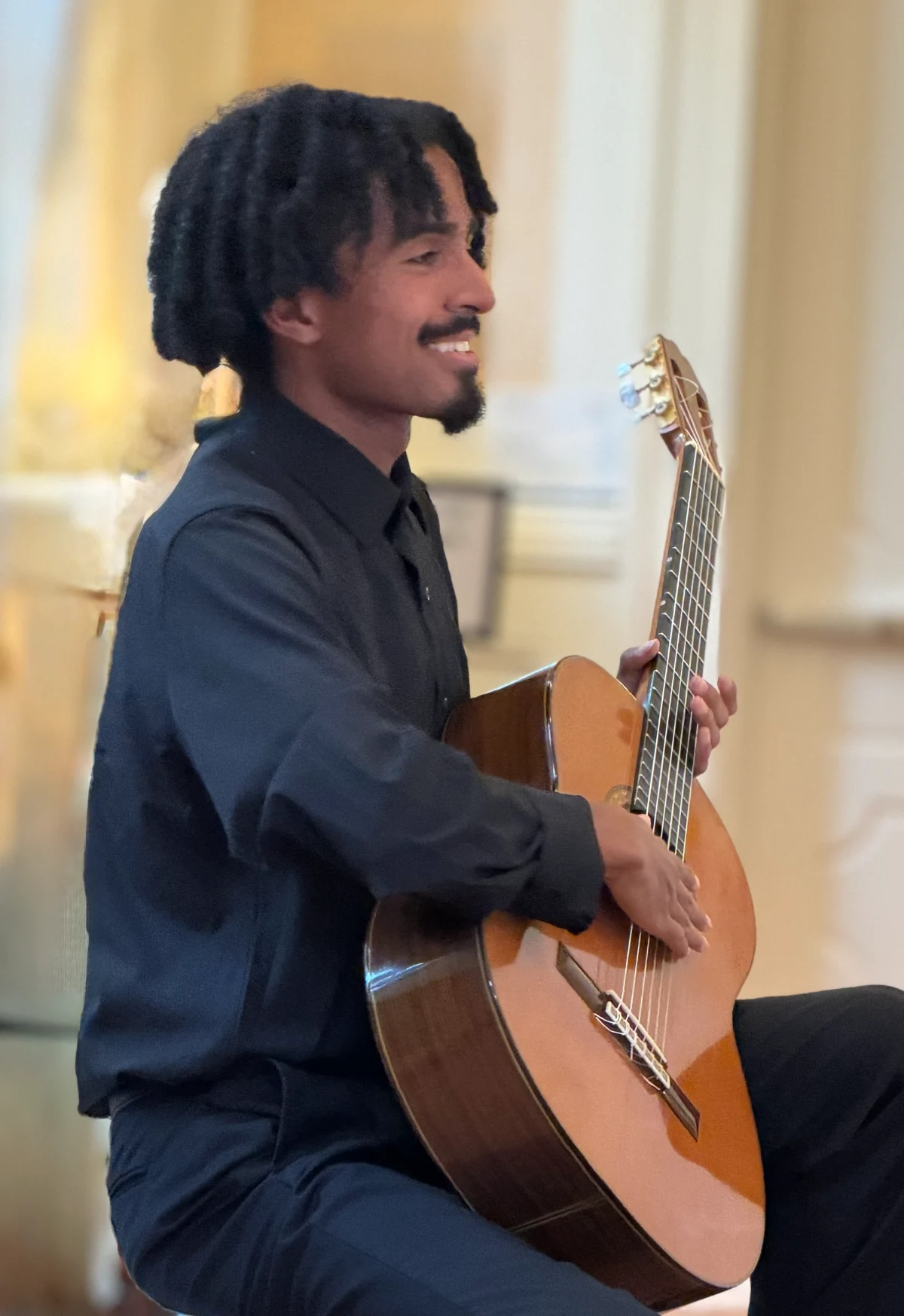 Darren Hayden smiling while holding an acoustic guitar.